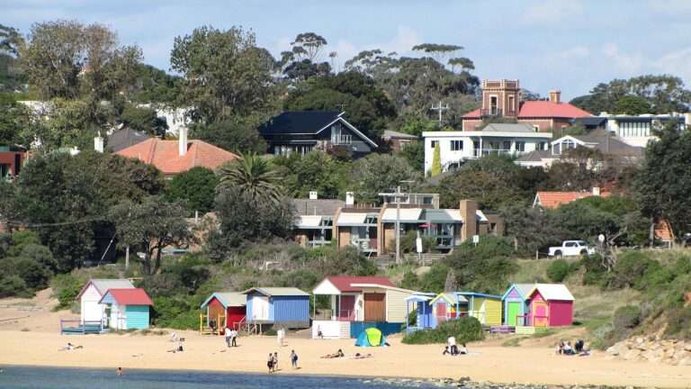 Colourful bathing boxes on the sand at Mornington with the village hill behind